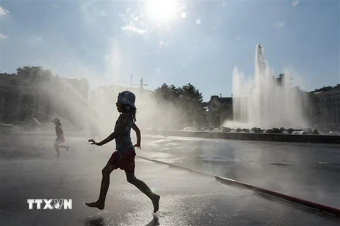 Trẻ em chơi đùa tại khu vực đài phun nước ở quảng trường Schwarzenberg, Áo để tránh nắng nóng với nhiệt độ lên tới 36 độ C, ngày 26/6/2019. (Nguồn: THX/TTXVN) 