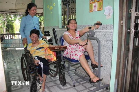 Bà Trần Thị Như Yến (xã Trà Côn, huyện Trà Ôn) và hai con bị nhiễm chất độc da cam luyện tập phục hồi chức năng. (Ảnh: Lê Thúy Hằng/TTXVN) 