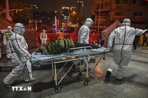 Nhân viên y tế chuyển bệnh nhân nhiễm virus corona gây viêm phổi tới bệnh viện Chữ thập Đỏ ở Vũ Hán, tỉnh Hồ Bắc ngày 25/1/2020. (Nguồn: AFP/TTXVN) 