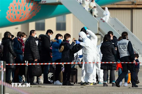 Các hành khách được kiểm tra thân nhiệt sau khi máy bay sơ tán họ từ Vũ Hán, Trung Quốc hạ cánh xuống căn cứ quân sự Istres ở tỉnh Bouches-du-Rhône, miền Nam Pháp ngày 2/2/2020. (Nguồn: AFP/TTXVN) 