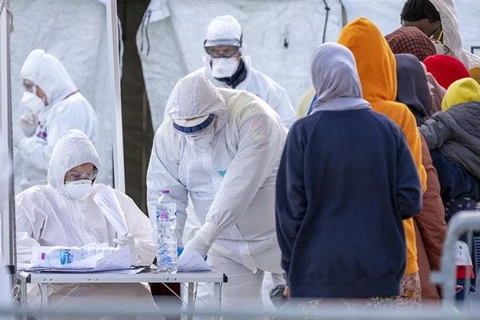 Nhân viên Hội Chữ thập đỏ Italy trong trang phục bảo hộ chống virus SARS-CoV-2 khi tiếp nhận người di cư được giải cứu trên Địa Trung Hải tại khu cảng ở Messina, Sicily ngày 27/2/2020. (Nguồn: AFP/TTXVN) 