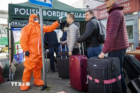 Nhân viên y tế kiểm tra thân nhiệt hành khách đi qua cửa khẩu biên giới Đức-Ba Lan, từ thị trấn Frankfurt tới Slubice nhằm ngăn ngừa dịch COVID-19 lây lan, ngày 16/3/2020. (Nguồn: AFP/TTXVN) 