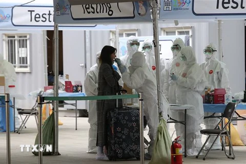 Nhân viên y tế lấy mẫu bệnh phẩm xét nghiệm COVID-19 đối với hành khách đến từ châu Âu tại sân bay quốc tế Incheon, phía Tây thủ đô Seoul, Hàn Quốc, ngày 26/3/2020. (Nguồn: Yonhap/TTXVN) 