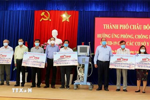 Đại diện lãnh đạo tỉnh An Giang và thành phố Châu Đốc trao bảng tượng trưng gói hỗ trợ thiết bị y tế trị giá 30 tỷ đồng cho các bệnh viện tuyến đầu chống dịch COVID-19. (Ảnh: Công Mạo/TTXVN) 