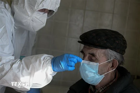 Nhân viên y tế giúp đeo khẩu trang cho một cụ ông 85 tuổi mắc COVID-19 tại Palagano, Italy, ngày 9/4/2020. (Nguồn: AFP/TTXVN) 
