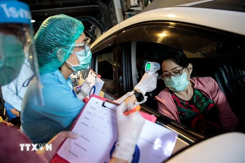 Nhân viên y tế kiểm tra thân nhiệt hành khách tại trạm xét nghiệm ở Bangkok, Thái Lan ngày 25/3/2020. (Nguồn: AFP/TTXVN) 
