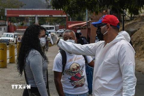 Nhân viên y tế kiểm tra thân nhiệt người dân nhằm ngăn chặn sự lây lan của dịch COVID-19 tại Caracas, Venezuela ngày 18/3/2020. (Nguồn: AFP/TTXVN) 