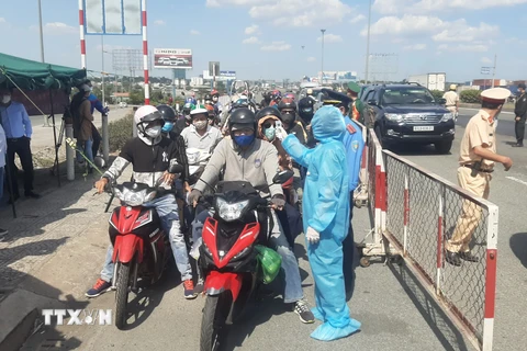 Nhân viên y tế đo thân nhiệt người ra vào Thành phố Hồ Chí Minh tại chốt kiểm dịch. (Ảnh: Đinh Hằng/TTXVN) 