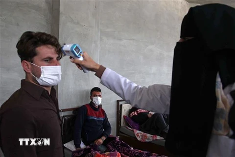 Nhân viên y tế kiểm tra thân nhiệt nhằm ngăn chặn sự lây lan của dịch COVID-19 tại Idlib, Syria, ngày 27/4/2020. (Nguồn: AFP/TTXVN) 