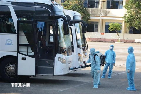 Nhân viên y tế phun thuốc khử trùng vào xe chở công dân từ Hàn Quốc trở về. (Ảnh: Văn Dũng/TTXVN) 
