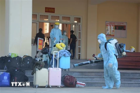 Nhân viên y tế phun thuốc khử trùng vào các vật dụng, hành lý của công dân từ Hàn Quốc trở về. (Ảnh: Văn Dũng/TTXVN) 