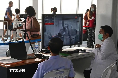 Nhân viên kiểm tra thân nhiệt hành khách bằng máy quét thân nhiệt tại sân bay quốc tế Wattay ở Vientiane, Lào. (Nguồn: AFP/TTXVN) 