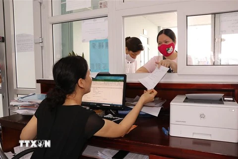 Người dân giao dịch tại quầy Bảo hiểm xã hội tỉnh Bắc Ninh. (Ảnh: Đinh Văn Nhiều/TTXVN) 