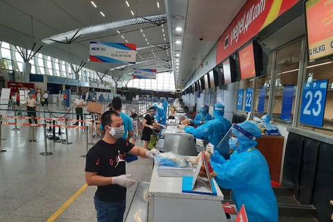 Nhân viên mặt đất của Hãng hàng không Vietjet phát quần áo bảo hộ miễn phí cho hành khách rời Đà Nẵng. (Nguồn: Vietnam+) 