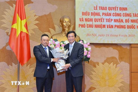 Chủ nhiệm Văn phòng Quốc hội Nguyễn Hạnh Phúc (bên phải) trao Quyết định của Bộ Chính trị, Nghị quyết của Ủy ban Thường vụ Quốc hội và tặng hoa chúc mừng ông Trần Sỹ Thanh. (Nguồn: TTXVN)