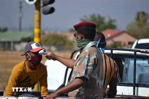 Binh lính Nam Phi kiểm tra thân nhiệt cho một người dân tại ngoại ô thủ đô Pretoria, Nam Phi. (Ảnh: Phi Hùng/TTXVN) 