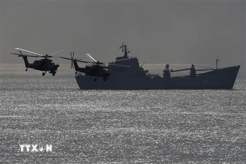 Tàu chiến và trực thăng quân sự của Nga. (Nguồn: AFP/TTXVN) 