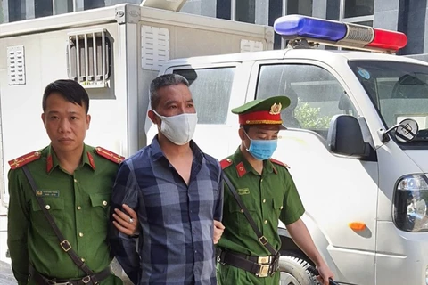 Lực lượng cảnh sát dẫn giải Nguyễn Văn Trung (ở giữa) vào phòng xử. (Nguồn: laodong.vn) 