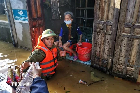 Lực lượng công an huyện Lệ Thủy lội nước, đưa hàng cứu trợ đến những gia đình bị cô lập trong nước lũ. (Ảnh: Thành Đạt/TTXVN) 