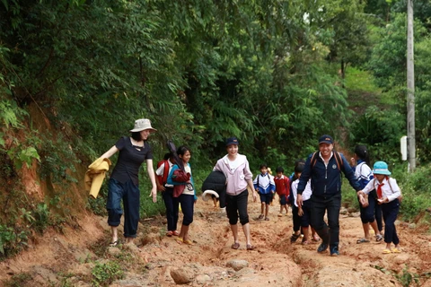Cô Hồ Thị Thùy Vân (ngoài cùng bên trái), cùng đồng nghiệp vận động đưa học sinh đến lớp. (Nguồn: baodantoc.vn) 
