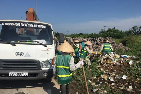 Công nhân Công ty Một thành viên Môi trường đô thị Hà Nội thu dọn rác thải bị đổ trộm tại Đại lộ Thăng Long. (Ảnh: Mạnh Khánh/TTXVN) 