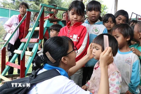 Các em học sinh nhóm thiện nguyện Fly to Sky chải tóc cho trẻ em làng Đê Kôn. (Ảnh: Hồng Điệp/TTXVN) 