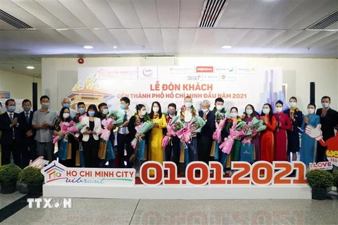 Hành khách và đại diện ngành Du lịch Thành phố Hồ Chí Minh tại Lễ đón khách đến Thành phố Hồ Chí Minh đầu năm 2021. (Ảnh: Mỹ Phương/TTXVN)