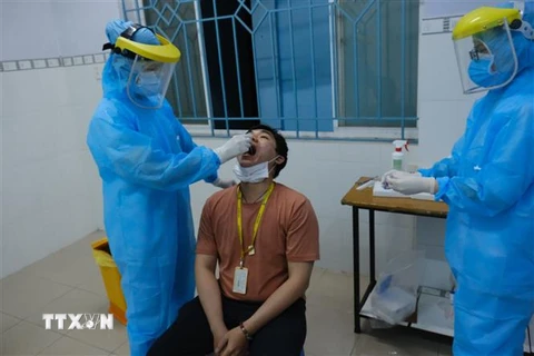 Nhân viên y tế quận Bình Thạnh lấy mẫu xét nghiệm cho người làm việc tại sân bay Tân Sơn Nhất, tối 7/2. (Ảnh: Đinh Hằng/TTXVN)