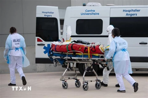 Nhân viên y tế chuyển bệnh nhân COVID-19 lên xe cứu thương tại Angers, Pháp ngày 15/3/2021. (Nguồn: AFP/TTXVN) 