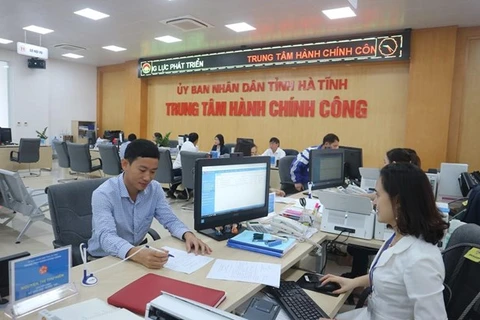 Cán bộ Trung tâm hành chính công tỉnh Hà Tĩnh giải quyết thủ tục hành chính cho người dân. (Ảnh: Hoàng Ngà/TTXVN) 