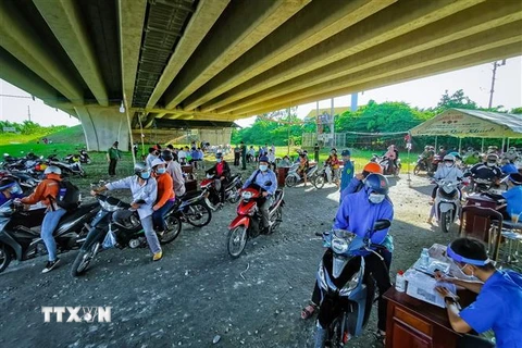 Người dân khai báo thông tin tại chốt kiểm soát dưới cầu Vàm Cống, quận Thốt Nốt. (Ảnh: Thanh Liêm/TTXVN) 