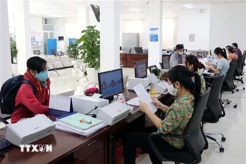 Cán bộ công chức Trung tâm Phục vụ hành chính công tỉnh Ninh Thuận giải quyết hồ sơ, thủ tục hành chính cho các doanh nghiệp. (Ảnh: Công Thử/TTXVN) 