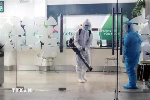 Lực lượng chức năng phun thuốc khử khuẩn trụ sở Ngân hàng Vietcombank, thành phố Thái Nguyên nơi chị T đã từng đến. (Ảnh: Trần Trang/TTXVN) 