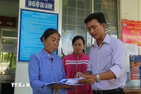 Cán bộ xã Tân Long (sáp nhập từ 2 xã Tân Lập và Long Thành), thuộc huyện Thủ Thừa, hướng dẫn người dân làm thủ tục hành chính. (Ảnh: Thanh Bình/TTXVN) 