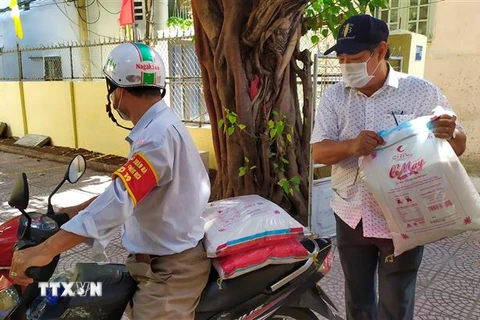 Đảng viên chi bộ khu dân cư Xuân Đán 5 tham gia Ban điều hành dân phố vận chuyển gạo đi phát cho hộ dân trong khu dân cư. (Ảnh: Trần Lê Lâm/TTXVN) 