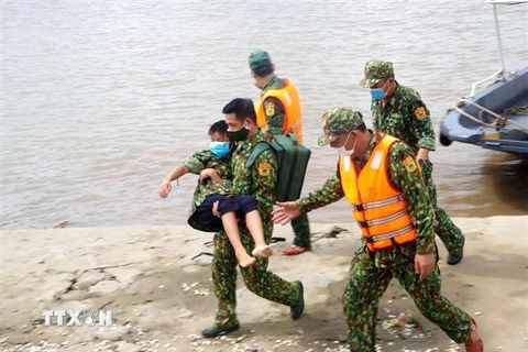 Lực lượng Quân y Biên phòng đưa các nạn nhân vào bờ và kiểm tra sức khỏe cho các nạn nhân. (Ảnh: TTXVN) 
