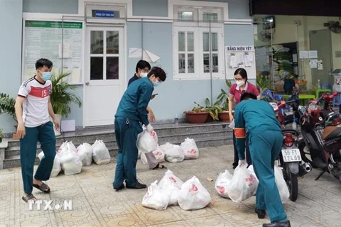 Lực lượng tại địa phương tiếp nhận và tổ chức phân phối đơn hàng đi chợ hộ đến người dân. (Ảnh: TTXVN phát) 