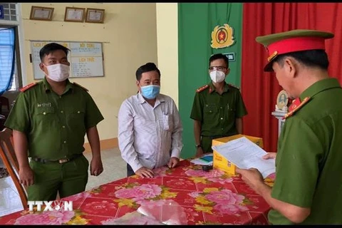 Cơ quan Cảnh sát điều tra Công an huyện Phú Tân (An Giang) đọc quyết định khởi tố vụ án, khởi tố bị can và bắt tạm giam đối với bị can Nguyễn Phước Linh (áo trắng). (Ảnh: TTXVN phát) 