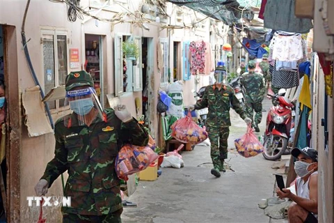 Cán bộ, chiến sỹ Trung đoàn 31, Sư đoàn 309 (Quân đoàn 4) chuyển quà cho nhân dân vùng dịch ở phường 16, Quận 8, TP Hồ Chí Minh. (Ảnh: Thanh Vũ/TTXVN) 