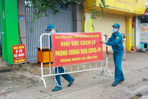 Lực lượng chức năng thực hiện dỡ bỏ phong tỏa cho 20 hộ dân tại khu phố 2, phường Xuân Thanh. (Ảnh: Lê Xuân/TTXVN) 