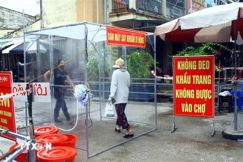 Người dân phải qua buồng khử khuẩn tự động trước khi vào mua hàng tại một chợ ở tỉnh Nghệ An. (Ảnh: Tá Chuyên/TTXVN) 