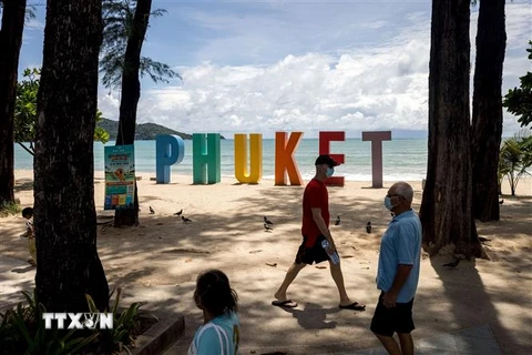 Du khách dạo chơi trên bãi biển ở Phuket, Thái Lan, ngày 14/8/2021. (Ảnh: AFP/TTXVN) 