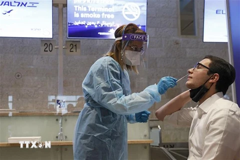 Nhân viên y tế lấy mẫu xét nghiệm COVID-19 cho người dân tại Tel Aviv, Israel. (Ảnh: AFP/TTXVN) 
