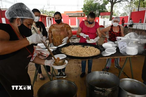 Tình nguyện viên phân phát suất ăn miễn phí cho người dân tại Asuncion, Paraguay trong bối cảnh dịch COVID-19 lan rộng. (Ảnh: AFP/TTXVN) 