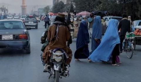 Một nhóm phụ nữ băng qua đường khi các thành viên của Taliban lái xe qua Kabul, Afghanistan. (Nguồn: Reuters) 