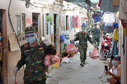 Cán bộ, chiến sỹ Trung đoàn 31, Sư đoàn 309 (Quân đoàn 4) chuyển quà cho nhân dân vùng dịch ở phường 16, quận 8, Thành phố Hồ Chí Minh. (Ảnh: Thanh Vũ/TTXVN) 