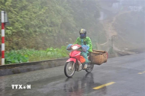 Người dân đi xe máy vận chuyển hàng hóa trong sương sớm, giá lạnh trên đỉnh đèo Pha Đin, Điện Biên. (Ảnh: Xuân Tiến/TTXVN) 