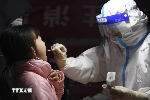 Nhân viên y tế lấy mẫu xét nghiệm COVID-19 cho một em nhỏ tại Thiểm Tây, Trung Quốc ngày 25/12. (Ảnh: THX/TTXVN) 