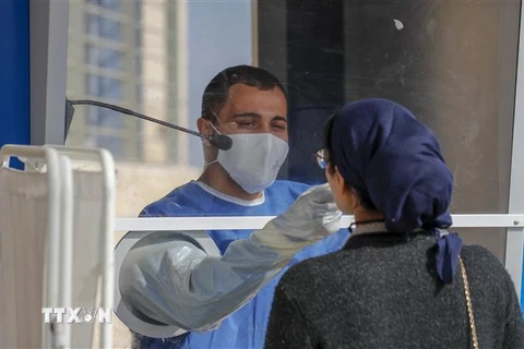 Nhân viên y tế Israel lấy mẫu xét nghiệm COVID-19 cho người dân tại Jerusalem. (Ảnh: AFP/TTXVN) 