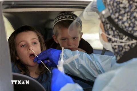 Nhân viên y tế Israel lấy mẫu xét nghiệm COVID-19 cho trẻ em tại Jerusalem. (Ảnh: AFP/TTXVN) 